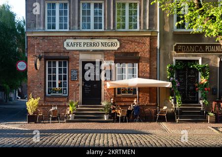 Danzig, Polen - 22. Mai 2022: Café-Fassade in der Abendsonne. Altstadt in Europa bei Sonnenuntergang Stockfoto