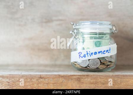 Münzen und Dollarscheine im Glasglas mit Rentenetikett für ein finanziell sparendes Konzept Stockfoto