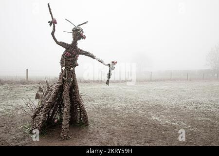 Die Korbhexenskulptur bei den Rollright Stones in Oxfordshire an einem kalten, nebligen Wintertag. Stockfoto