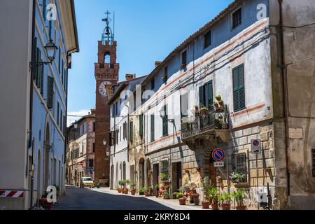 Sehen Sie den Corso Giacomo Matteotti mit dem Uhrenturm Torre della Mencia in der Ferne in Asciano auf Kreta Senesi, Provinz Siena, Toskana, Italien Stockfoto
