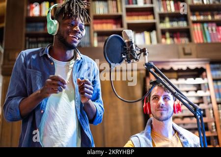 Der junge Künstler Sänger Afro-American Rapper tritt während einer Web-Radio-Übertragung auf, Live-Streaming organisiert in der häuslichen Umgebung mit moderner Technik Stockfoto