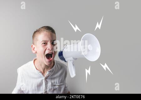 Süßer Teenager in einem weißen Hemd, der Megafon benutzt und auf grauem Hintergrund schreit. Stockfoto