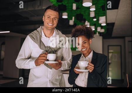 Glücklicher Mann und glückliche Frau mit Kaffee, die in die Kamera schauen Stockfoto