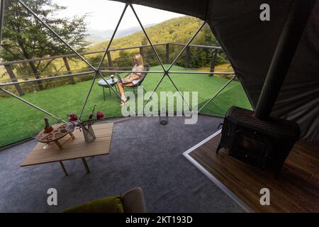 Frau, die an einem Laptop arbeitet Outdoor Bubble Tent House Dome - Naturreisekonzept. Stockfoto