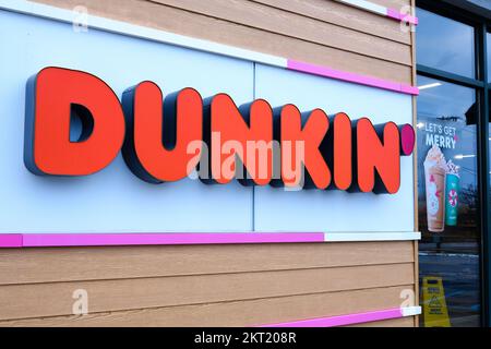ELLENBURG, NEW YORK, USA - 19. NOVEMBER 2022: An einem Dunkin’ Donuts loc werden Feiertagsgetränke neben einem Schild mit der Wortmarke Dunkin’ angepriesen Stockfoto