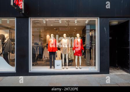 Drei Puppen in einem Schaufenster, die zu Weihnachten Party-Outfits tragen (Nov22) Stockfoto