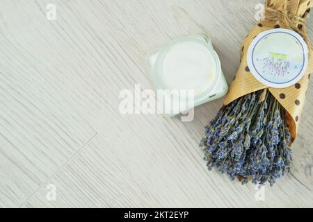 Handgefertigte kosmetische Cremebecher und getrocknete Lavendelblumen auf hellem Hintergrund. Bio-organische Kosmetik. Pflanzenbasis. Stockfoto