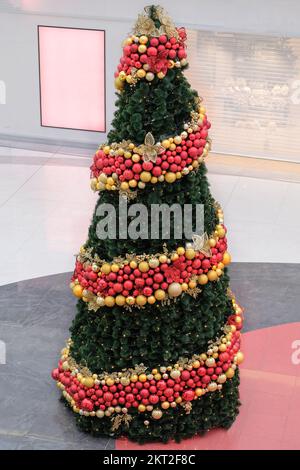 Weihnachtsbaum im großen Einkaufszentrum. Frohe Neujahrsferien. Traditionell dekoriert und mit Lichtern. Weihnachtsdekoration Glaskoffer. Stockfoto