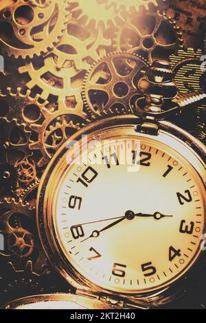 Metall, Retro-Uhr mit weißem Ziffernblatt, antikes Uhrwerk mit Zahnrädern im Hintergrund. Zahnräder der Zeitreise Stockfoto