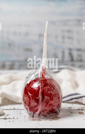 Apfelbonbons oder rote Toffees. Zuckeräpfel mit Sirup auf weißem Holzhintergrund. Schließen Stockfoto