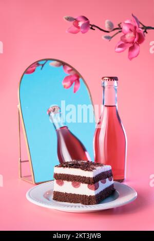 Schokoladenkuchen mit Sauerkirschen. Ein Stück Kuchen auf einem Teller mit Gabel. Süßes Dessert auf pinkfarbenem Hintergrund mit leuchtenden Pflaumenblüten in Magenta. Stockfoto