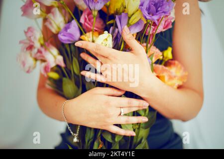 Frauenhände halten Blumen in den Händen. Mädchen mit Schmuck, Ringen und Armband. Ein Blumenstrauß für eine Frau auf einem Feiertag am 14. Februar, 8. März Stockfoto