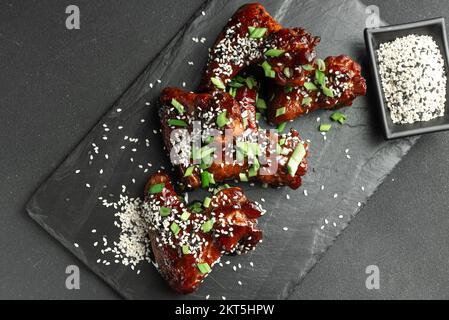 Hühnerflügel. Traditionelles asiatisches Rezept. Dunkler Hintergrund. Draufsicht. Hähnchenflügel in Teriyaki-Sauce. Asiatische Chicken Wings auf dunklem Hintergrund. Hühnchen Stockfoto