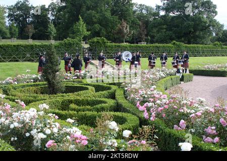 Dumfries House, Cumnock, Scotland UK, Ayr Pipe Band spielen vor dem Haus. Sie spielten für Gäste, die im Haus unterhalten wurden. Dumfries House ist ein Palladianisches Landhaus in Ayrshire, Schottland. Es befindet sich auf einem großen Anwesen, rund 3 Meilen westlich von Cumnock. Der Brunnen, auch bekannt als Mahfouz-Brunnen. Eine Seuche in der Nähe sagt: " Möglich durch die Großzügigkeit VON MAHFOUZ Marei Murbank bin Mahfouz. Der Brunnen wurde offiziell eröffnet von H. R.H. dem Prinzen Charles, Herzog von Rothesay am 21. Oktober 2014. Stockfoto