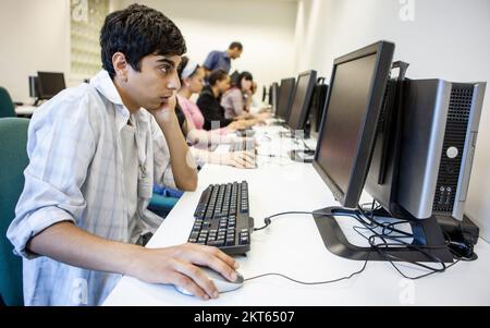 Computerstudien; Online-Lernen. Ein verstorbener Teenager-Indianer in der Klasse, der seine College-Computersuite benutzt. Aus einer Reihe von zugehörigen Bildern. Stockfoto