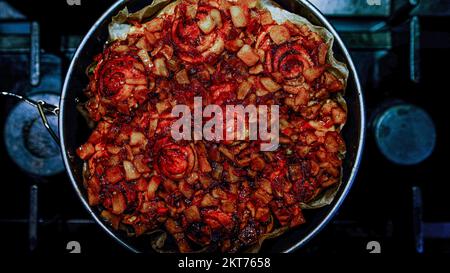 Hausgemachter roter leckerer Apfelkuchen auf dunklem Herdhintergrund im Backkreis Stockfoto