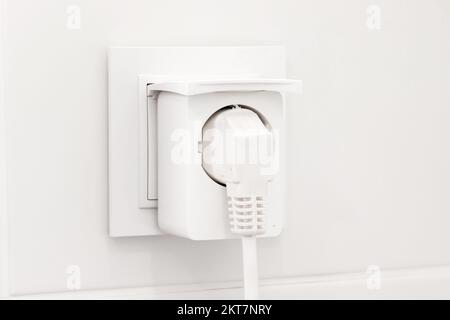 Weiße europäische Steckdose mit intelligentem Stecker im modernen, hellen Badezimmer mit weiß gefliesten Wänden Stockfoto