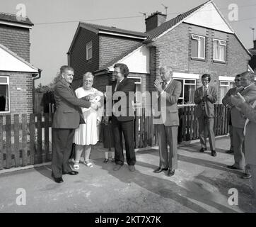 1980er, neues Haus, auf einem Bürgersteig auf einem Wohngebiet für ein Werbefoto, mehrere passende Firmenmanager, die klatschen, während die Schlüssel zu einem neuen Zuhause einem Gentleman in England, Großbritannien, übergeben werden. Stockfoto