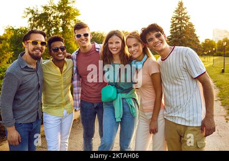 Porträt von glücklichen und sorgenfreien, vielfältigen jungen Menschen, die im Sommer im Park zusammen posieren. Stockfoto