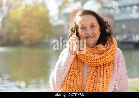 Eine glückliche, alte Weiße, die draußen telefoniert. Platz für Text. Stockfoto