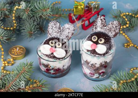 Kuchen in zwei Gläsern in Form von süßen Kaninchen mit Kirschen, Schokoladenkeks und Kokosflocken Stockfoto