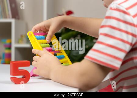 Ein kleines Kind lernt, sich auf Abakus, Mathematik, Arithmetik für Kinder zu verlassen. Stockfoto