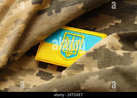 Pixeliges digitales Tarnmaterial mit ukrainischer Flagge und Wappen auf Chevron in Blau und Gelb. Attribute der ukrainischen Soldatenuniform Stockfoto