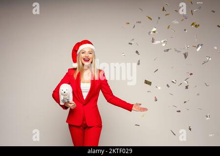 Elegante glückliche Frau in Santa Hut mit Konfetti. Stockfoto