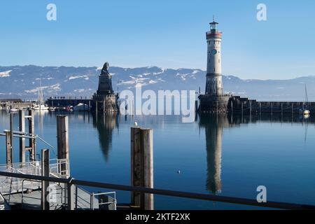 Hafen von Lindau am ruhigen, winterlichen Bodensee oder Bodensee mit den Alpen im Hintergrund an einem schönen Winterabend mit malerischem Himmel Stockfoto