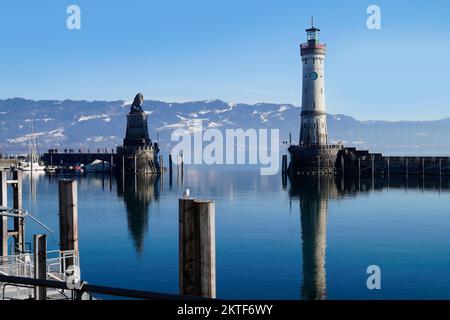 Hafen von Lindau am ruhigen, winterlichen Bodensee oder Bodensee mit den Alpen im Hintergrund an einem schönen Winterabend mit malerischem Himmel Stockfoto