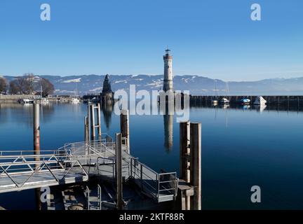 Hafen von Lindau am ruhigen, winterlichen Bodensee oder Bodensee mit den Alpen im Hintergrund an einem schönen Winterabend mit malerischem Himmel Stockfoto