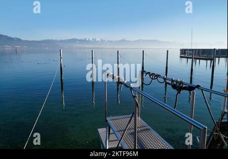 Hafen der Insel Lindau am ruhigen Bodensee oder Bodensee mit den Alpen im Hintergrund an einem schönen Winterabend mit malerischem Himmel Stockfoto