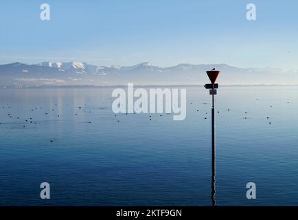 Hafen der Insel Lindau am ruhigen Bodensee oder Bodensee mit den Alpen im Hintergrund an einem schönen Winterabend mit malerischem Himmel Stockfoto