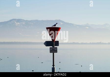 Hafen der Insel Lindau am ruhigen Bodensee oder Bodensee mit den Alpen im Hintergrund an einem schönen Winterabend mit malerischem Himmel Stockfoto