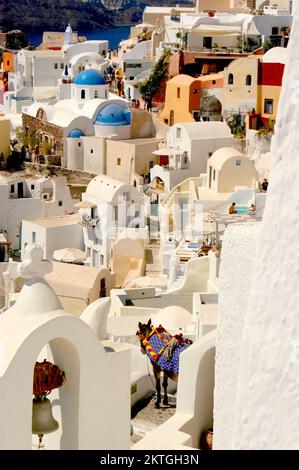 Das atemberaubende Dorf Oia, das aus Santorinis Klippen mit weißen Gebäuden und farbenfrohen Dächern vor dem tiefblauen Ägäischen Meer geschnitzt ist. Stockfoto