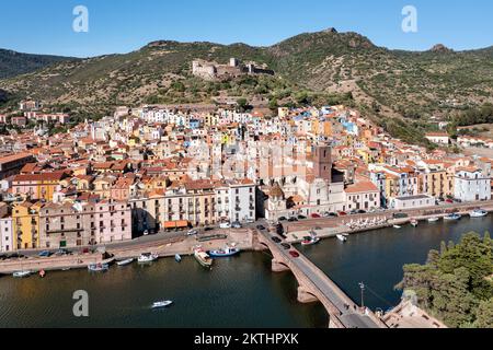 Luftaufnahme des Dorfes Bosa mit bunten Häusern und einer mittelalterlichen Burg in der Ferne auf der Insel Sardinien in Italien. Stockfoto