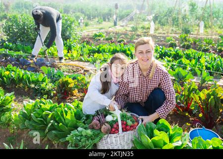 Eine Farmerin und ihre Tochter im Teenageralter halten einen Weidenkorb in der Hand Stockfoto