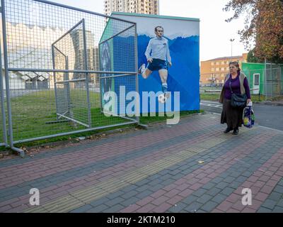 Batumi, Georgia. 11.23.2022 Eine Frau kommt in der Nähe des Stadions vorbei. Wunderschöner Ort. Stadion von außen. Sportanlage. Moderne Architektur Stockfoto