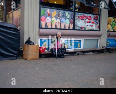 Batumi, Georgia. 11.21.2022 Bettler in der Stadt. Großmutter mit ausgestreckter Hand. Ein Mann sitzt an einer Wand auf der Straße. Er will Geld Stockfoto