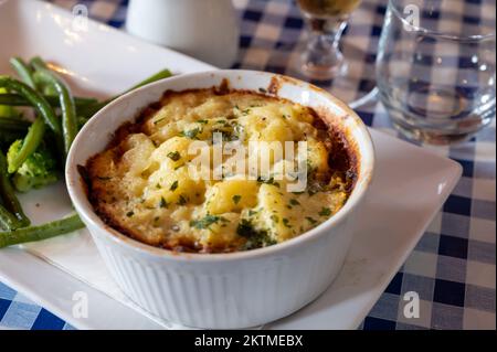 Gewürzte Linsen- und Pilzkuchen, langsam in Rotwein gekocht, mit Cheddar-Maische garniert und mit saisonalem Gemüse aus der Nähe serviert Stockfoto