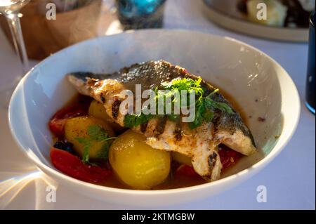Provenzalische Küche, gegrilltes Weißfischfilet vom Seabarsch, serviert mit Kartoffeln, Tomaten und Bouillabaisse-Fischjus im französischen Restaurant Stockfoto