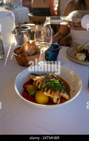 Provenzalische Küche, gegrilltes Weißfischfilet vom Seabarsch, serviert mit Kartoffeln, Tomaten und Bouillabaisse-Fischjus im französischen Restaurant Stockfoto