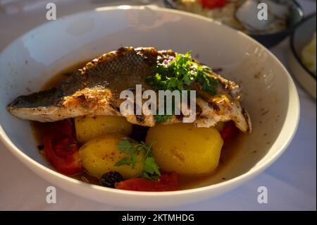 Provenzalische Küche, gegrilltes Weißfischfilet vom Seabarsch, serviert mit Kartoffeln, Tomaten und Bouillabaisse-Fischjus im französischen Restaurant Stockfoto