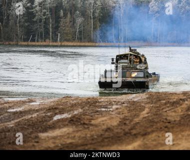 Die polnischen Soldaten, die der 20.. Brigade zugeteilt wurden, nutzen einen Army Medium Amphibious Transport, um ein UK zu transportieren Royal Lancers, Prince of Wales Truppe 2A Mobilitätswaffen-montiertes Einbausatz Fahrzeug über einem See bei amphibischen Angriffen während der Bull Run Trainingsübung in Bemowo Piskie, Polen, 24. November 2022. Die mechanisierte Brigade aus dem Jahr 20. arbeitet stolz mit der 1.. Infanteriedivision, NATO-Verbündeten und regionalen Sicherheitspartnern zusammen, um dem V-Corps unter Amerikas vorwärtsgerichtetem Korps in Europa kämpferische Kräfte zur Verfügung zu stellen. (USA Foto der Nationalgarde der Armee Stockfoto