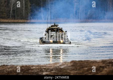 Die polnischen Soldaten, die der 20.. Brigade zugeteilt wurden, nutzen einen Army Medium Amphibious Transport, um ein UK zu transportieren Royal Lancers, Prince of Wales Truppe 2A Mobilitätswaffen-montiertes Einbausatz Fahrzeug über einem See bei amphibischen Angriffen während der Bull Run Trainingsübung in Bemowo Piskie, Polen, 24. November 2022. Die mechanisierte Brigade aus dem Jahr 20. arbeitet stolz mit der 1.. Infanteriedivision, NATO-Verbündeten und regionalen Sicherheitspartnern zusammen, um dem V-Corps unter Amerikas vorwärtsgerichtetem Korps in Europa kämpferische Kräfte zur Verfügung zu stellen. (USA Foto der Nationalgarde der Armee Stockfoto