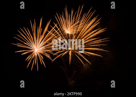 Goldenes und weißes Feuerwerk vor schwarzem Himmel bei Nacht. Stockfoto