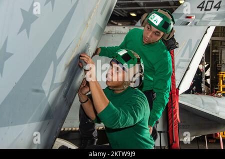 Philippinen-Meer. 21.. November 2022. Aviation Machinists Mate Airman Christopher Collins und Aviation Structural Mechanic 3. Class Malik Collins, beide aus Fitchburg, Massachusetts, führen eine Korrosionsprüfung an einer F/A-18E Super Hornet durch, die an Eagles of Strike Fighter Squadron (VFA) 115 in der Hangarbucht der USA befestigt ist Der einzige Flugzeugträger der Navys, USS Ronald Reagan (CVN 76), in der Philippinischen See, November. 21. Die Eagles führen Luftangriffe und Eskorte-Missionen der Streitkräfte sowie Schiffe, Gefechtsverbände und Nachrichtensammeloperationen durch. Ronald Rea Stockfoto