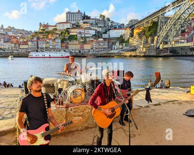 PORTO, PORTUGAL - 6. SEPTEMBER 2022: Band von Straßenmusikern spielt am Ufer von Gaia bei Sonnenuntergang, Stadtbild mit Ribeira und Dom Luis Brücke Stockfoto