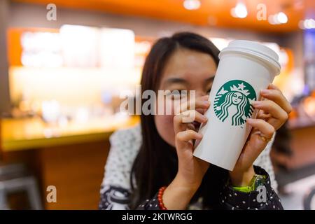 SHENZHEN, CHINA - 31. JANUAR 2015: Starbucks Gast hält eine Tasse Kaffee. Starbucks Corporation ist ein amerikanisches globales Kaffeeunternehmen und Kaffeehaus Stockfoto