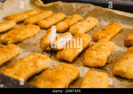 Knusprige panierte Fischstäbchen aus wild gefangenem Alaska-Pollock aus der Nähe auf einer Backpfanne, direkt aus dem Ofen Stockfoto